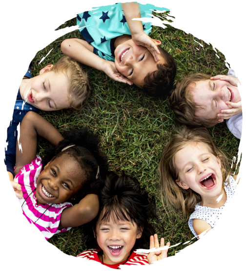 Laughing preschoolers lying on the ground in a circle