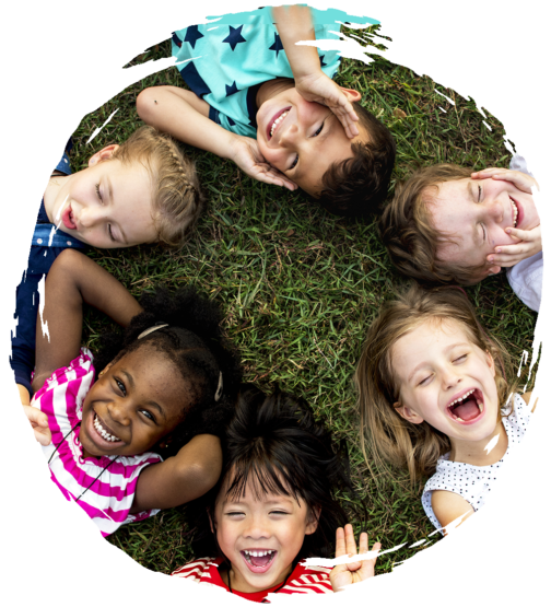 Laughing preschoolers lying on the ground in a circle